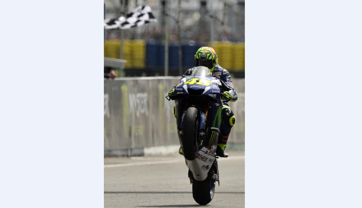 Pebalap Movistar Yamaha, Valentino Rossi, mengangkat roda depan motornya saat berhasil finis kedua dalam balapan MotoGP Prancis di Sirkuit Le Mans, Minggu (8/5/2016). (AFP/Jean-Francois Monier)