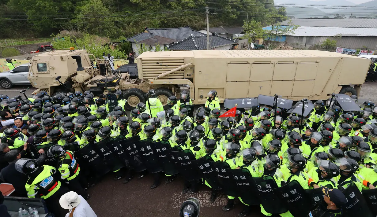 Pengunjuk rasa dan polisi berdiri ditepi jalan saat kendaraan yang membawa peralatan rudal THAAD AS melintas di Seongju, Korsel (26/4). Penempatan perangkat perang itu dilakukan menyusul meningkatnya ancaman dari Korea Utara. (AFP Photo/Yonhap)