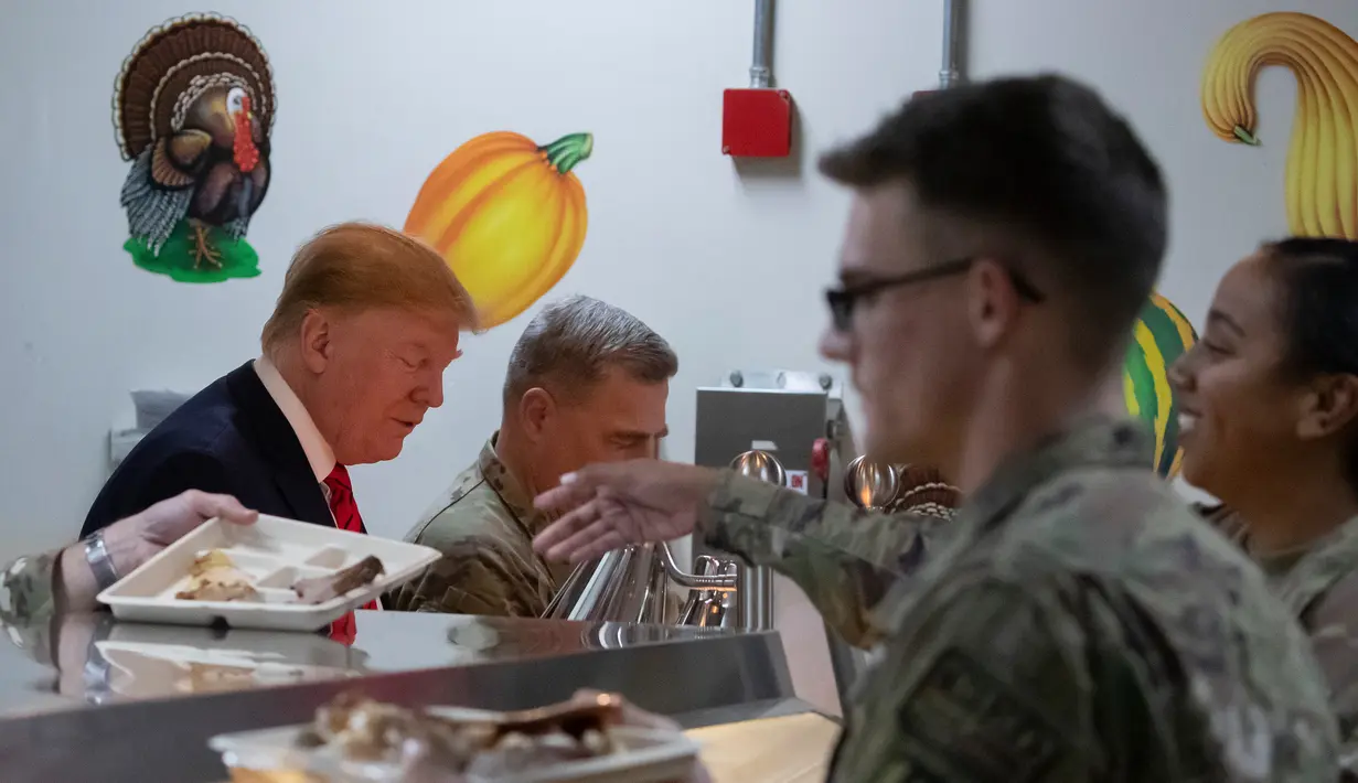 Presiden Amerika Serikat Donald Trump (kiri) mengambil makan malam saat mengunjungi Pangkalan Udara Bagram, Afghanistan, Kamis (28/11/2019). Kunjungan dadakan Trump pada hari Thanksgiving tersebut mengejutkan pasukan AS yang bertugas di Afghanistan. (AP Photo/Alex Brandon)