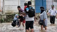 Banjir di kawasan Bukit Duri telah membuat seorang wanita terperosok ke dalam lubang yang tak terlihat karena tertutup oleh genangan air, Jakarta, Selasa (21/2). Tampak seorang lelaki membantu seorang wanita usai terperosok. (Liputan6.com/Yoppy Renato)