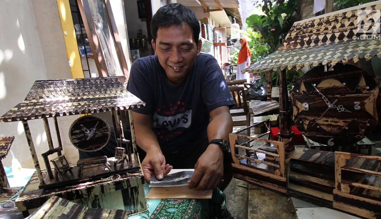 Perajin, Inoe Farhand melakukan finishing pengerjaan pembuatan miniatur jam dari pelepah pisang di Pamulang, Tangerang Selatan, Kamis (10/1). Kerajinan tangan Inoe hasilnya dijual ke sejumlah wiliyah JODETABEK hingga mancanegara. (Merdeka.com/Arie Basuki)