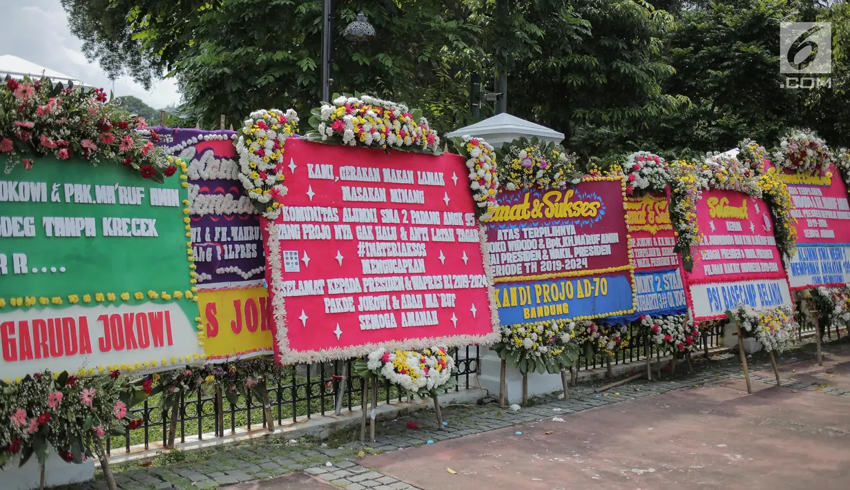 Sejumlah karangan bunga bertuliskan ucapan selamat untuk Joko Widodo (Jokowi) dan Ma'ruf Amin di depan pagar gedung Sekretariat Negara, Jakarta, Senin (22/4). Karangan bunga dari pendukung Jokowi-Ma'ruf tersebut ditujukan atas kemenangan pasangan itu pada Pilpres 2019. (Liputan6.com/Faizal Fanani)