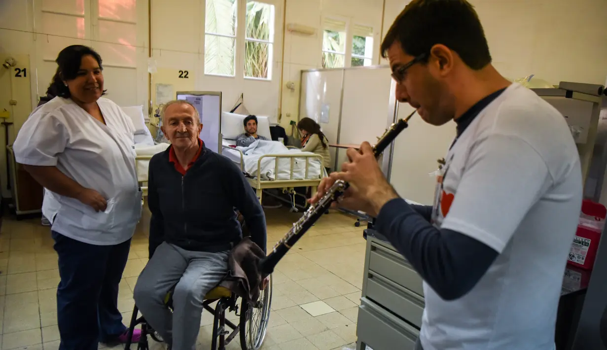 Pasien dan perawat menonton penampilan salah seorang relawan dari Musica Para el Alma di Rumah Sakit Alvarez di Buenos Aires, Argentina (12/6). Dibentuk lima tahun lalu, Musica Para el Alma kini beroperasi di 10 negara.  (AFP Photo/Eitan Abramovich)