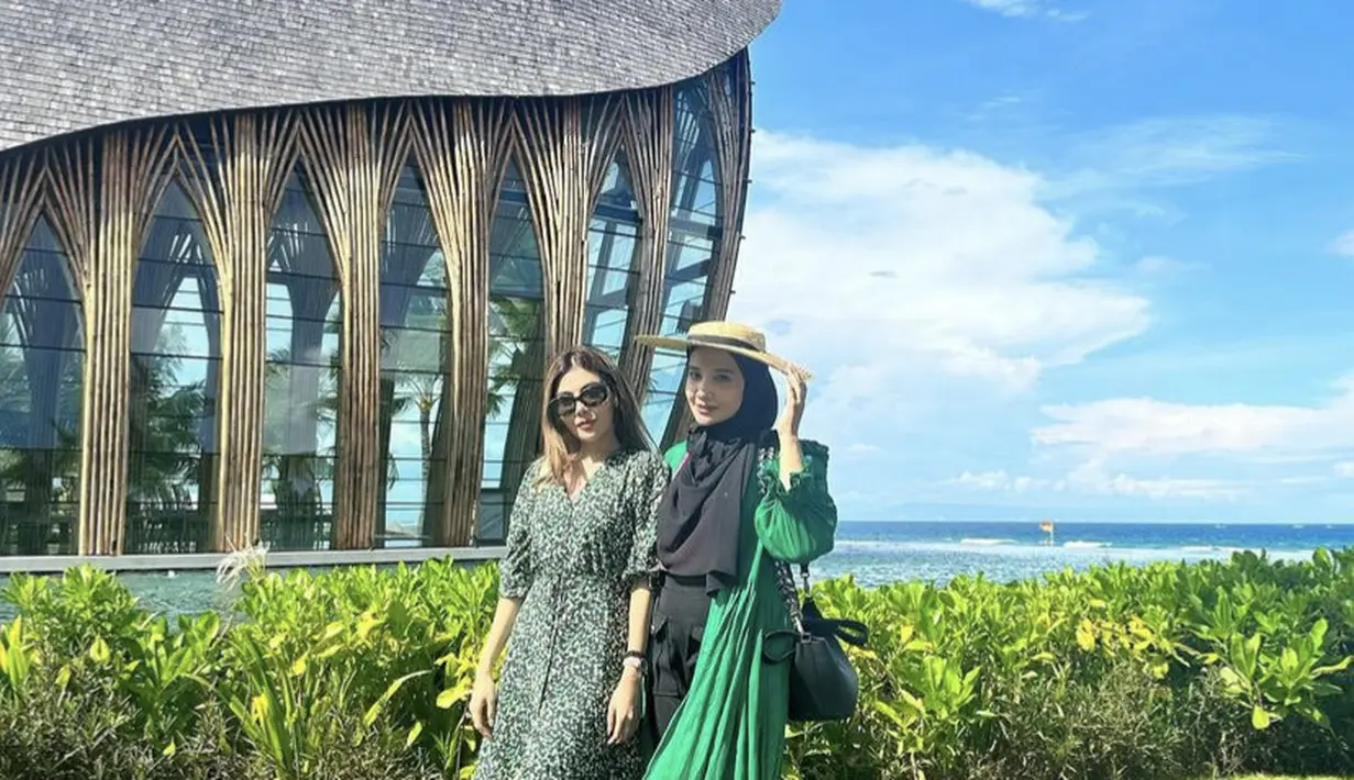 Zaskia Sungkar mengenakan dress hijau dipadukan kerudung hitam dan topi pantainya. [Instagram/@zaskiasungkar15]