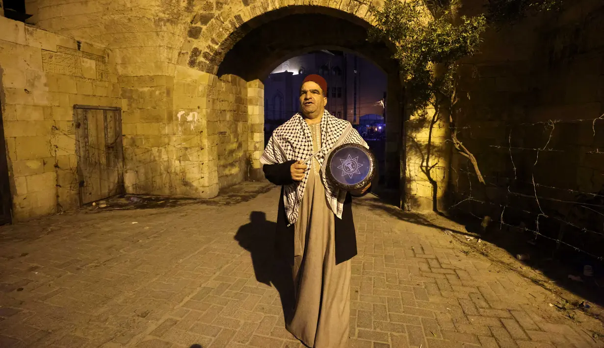 Nizar al-Dabbas Palestina berusia lima puluh tahun, seorang "Musaharati" yang memainkan peran tradisional sebagai "penabuh drum Ramadhan", membangunkan umat Islam untuk makan sahur sebelum fajar selama bulan suci Ramadhan di Khan Yunis di Jalur Gaza selatan (5/4/2022). (AFP/Said Khatib)