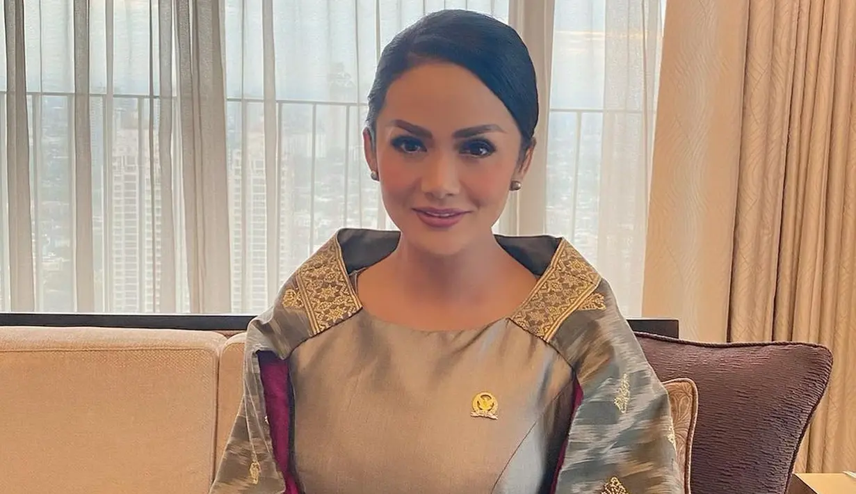 Krisdayanti juga pernah berkantor di DPR dengan mengenakan dress berkerah shanghai lebar yang dibuat dari kain tenun berwarna abu-abu. Motif tenun abu-abu ini dipadukan dengan tenun berwarna pink yang memberikan sentuhan kontras.