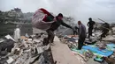 Warga mengumpulkan sisa-sisa barang milik mereka dari sebuah bangunan yang hancur akibat serangan Israel di desa Qennarit, Lebanon selatan, Kamis 22 Januari 2026. Israel kembali menyerang sejumlah desa di Lebanon selatan, termasuk Qanarit, Zrariyeh, dan Ansar. (AP Photo/Mohammed Zaatari)