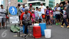 Pengamen perkusi memainkan alat musiknya yang terbuat dari ember bekas di kawasan Bundaran HI saat CFD, Jakarta, Minggu (10/9). Tidak hanya untuk olahraga, CFD juga menjadi sarana hiburan dan liburan murah di Jakarta. (Liputan6.com/Gempur M. Surya)