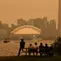 Warga memandang cakrawala pusat kota Toronto dari Kepulauan Toronto saat kabut asap akibat kebakaran hutan di Ontario Utara menyelimuti kota dan menurunkan kualitas udara, Toronto, Ontario, Kanada, Kamis, 15 Juli 2026. (AFP/ Cole Burston)
