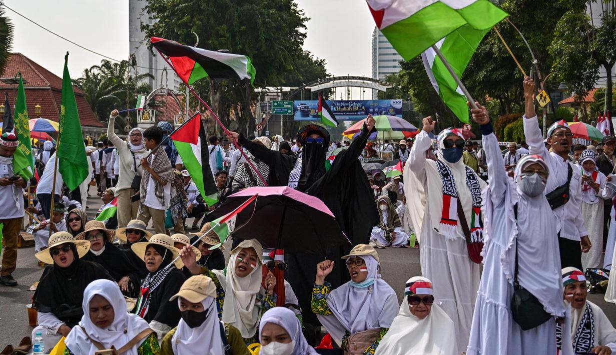 Para pengunjuk rasa melambaikan bendera Palestina dalam sebuah aksi unjuk rasa untuk menunjukkan dukungan kepada rakyat Palestina di Gaza, Surabaya, Jawa Timur pada 19 April 2025. (JUNI KRISWANTO/AFP)