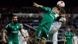Pemain Real Madrid, Karim Benzema dan pemain Leganes, Unai Bustinza berebut menyundul bola pada leg kedua perempatfinal Copa del Rey di Santiago Bernabeu, Kamis (25/1). Bermain di kandang sendiri, Real Madrid menyerah 1-2. (AP/Francisco Seco)