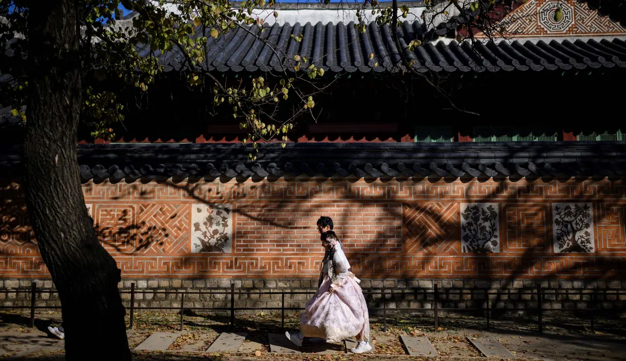 Orang-orang mengenakan Hanbok (pakaian tradisional Korea) saat mereka mengunjungi halaman Istana Gyeongbokgung di Seoul pada tanggal 2 November 2023. (ANTHONY WALLACE/AFP)