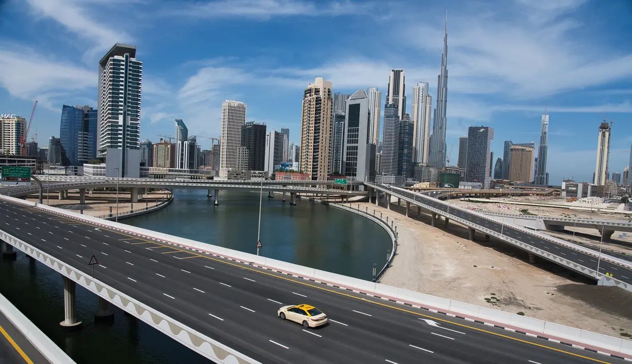 <p>Sebuah taksi melintasi jalan raya yang sepi dekat Burj Khalifa di Dubai, Uni Emirat Arab, Senin (6/4/2020). Pemerintah Dubai memberlakukan lockdown selama dua pekan untuk mengantisipasi penyebaran virus corona COVID-19. (AP Photo/Jon Gambrell)</p>