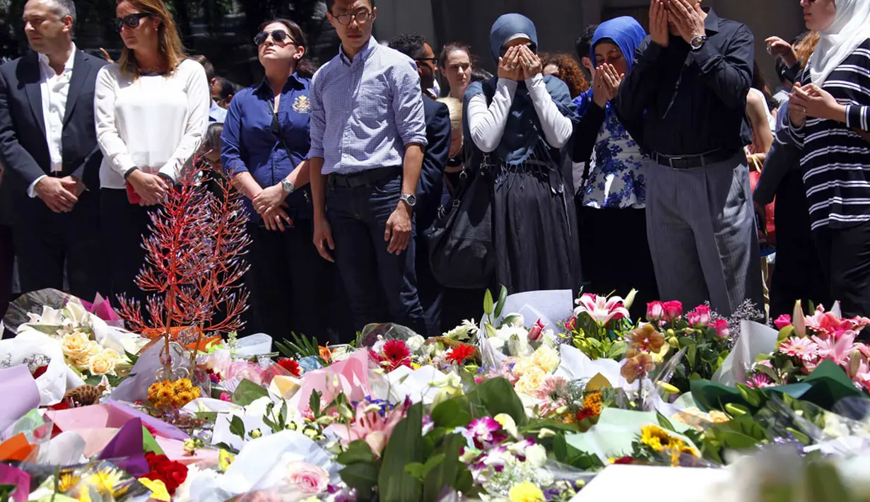 Sejumlah kaum muslim berdoa di dekat tumpukan karangan bunga untuk menghormati korban tewas dalam penyanderaan yang terjadi di Kafe Lindt, Sidney, Australia (16/12/2014). (REUTERS/David Gray)