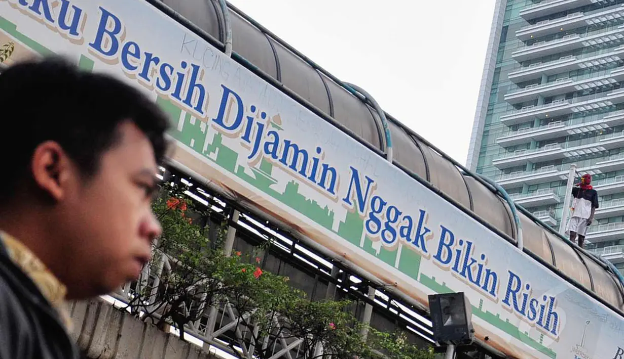 Salah satu pengguna jalan MH Thamrin memerhatikan tingkah nekat orang yang tidak dikenal di atas JPO di sekitar Bundaran HI, Jakarta, (25/7/2014). (Liputan6.com/Faizal Fanani)