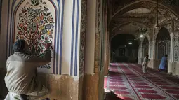 Salah satu persiapan yang dilakukan umat Muslim di Peshawar, Pakistan, adalah dengan membersihkan masjid bersejarah, Mahabat Khan. Tampak dalam foto, seorang pelukis memberikan sentuhan akhir pada sebuah karya seni sementara para pekerja membersihkan area masjid bersejarah Mahabat Khan sebagai persiapan untuk bulan puasa Ramadan yang akan datang, di Peshawar, Pakistan, Senin, 16 Februari 2026. (AP Photo/Muhammad Sajjad)