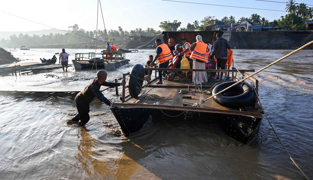 Dan, sebagai bentuk kepedulian dan keberpihakan terhadap kondisi siswa, Disdikbud Kabupaten Bireuen juga memberikan kelonggaran, termasuk aturan berpakaian. Tampak dalam foto, Masyarakat menggunakan perahu darurat untuk menyeberangi Sungai Peusangan pasca banjir bandang yang menghancurkan desa-desa di sekitarnya di kabupaten Bireuen, provinsi Aceh, Indonesia pada Senin 5 Januari 2026. (CHAIDEER MAHYUDDIN/AFP)