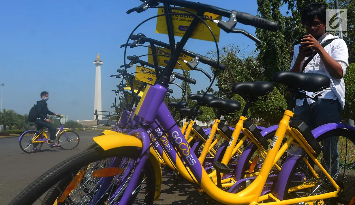 Pengunjung bermain handphone saat akan menggunakan sepeda dari layanan bike sharing di Monas, Jakarta, Jumat (27/7). Dari aplikasi GOWES, cukup memindai QR Code yang terletak di bagian belakang sepeda agar kuncinya terbuka. (Merdeka.com/Imam Buhori)