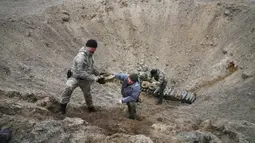 Pencari ranjau dari Kementerian Dalam Negeri Ukraina menyiapkan bahan peledak pada sebuah lubang untuk meledakkannya dekat ladang ranjau setelah pertempuran baru-baru ini di Desa Moshchun, dekat Kiev, Ukraina, 19 April 2022. (AP Photo/Efrem Lukatsky)