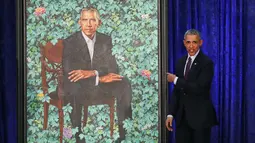 Presiden AS ke-44 Barack Obama menujuk lukisan dirinya saat upacara peresmian di Galeri Potret Nasional Smithsonian, Washington DC (12/2). Potret Presiden Obama ini dibuat oleh Kehinde Wiley. (Mark Wilson/Getty Images/AFP)