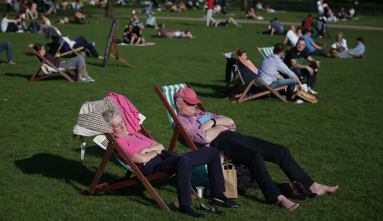 Warga Inggris berjemur di sebuah taman di pusat kota London,  Inggris, Sabtu (8/4). Sinar matahari yang hangat dimanfaatkan warga Inggris untuk berjemur dan bersantai dengan keluarga atau teman di taman-taman kota. (AFP PHOTO / Daniel Leal-Olivas)