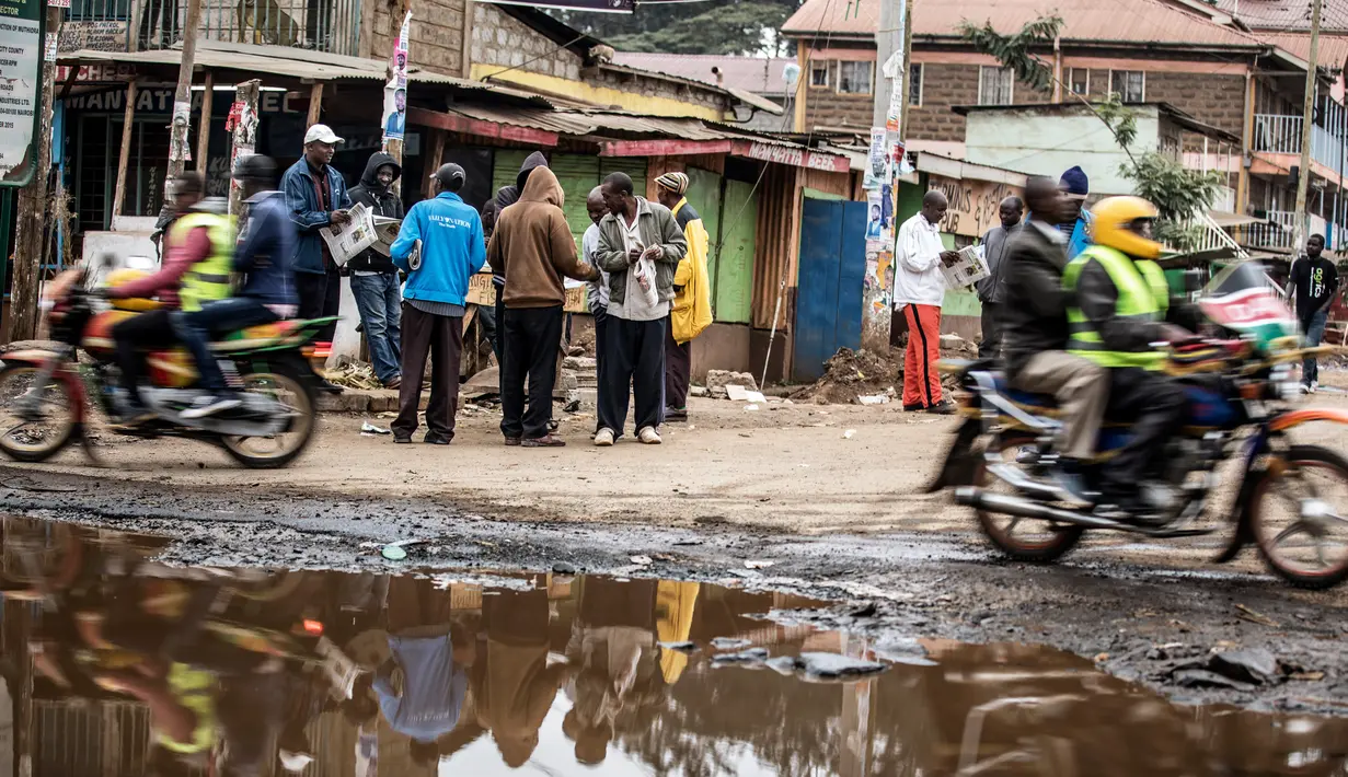 Sejumlah warga membaca koran di daerah kumuh Kawangare di Nairobi (10/8). Warga Kenya tengah gelisah menunggu hasil pemilihan presidennya, antara Uhuru Kenyatta dan pesaingnya, Raila Odinga. (AFP Photo/Tobin Jones)