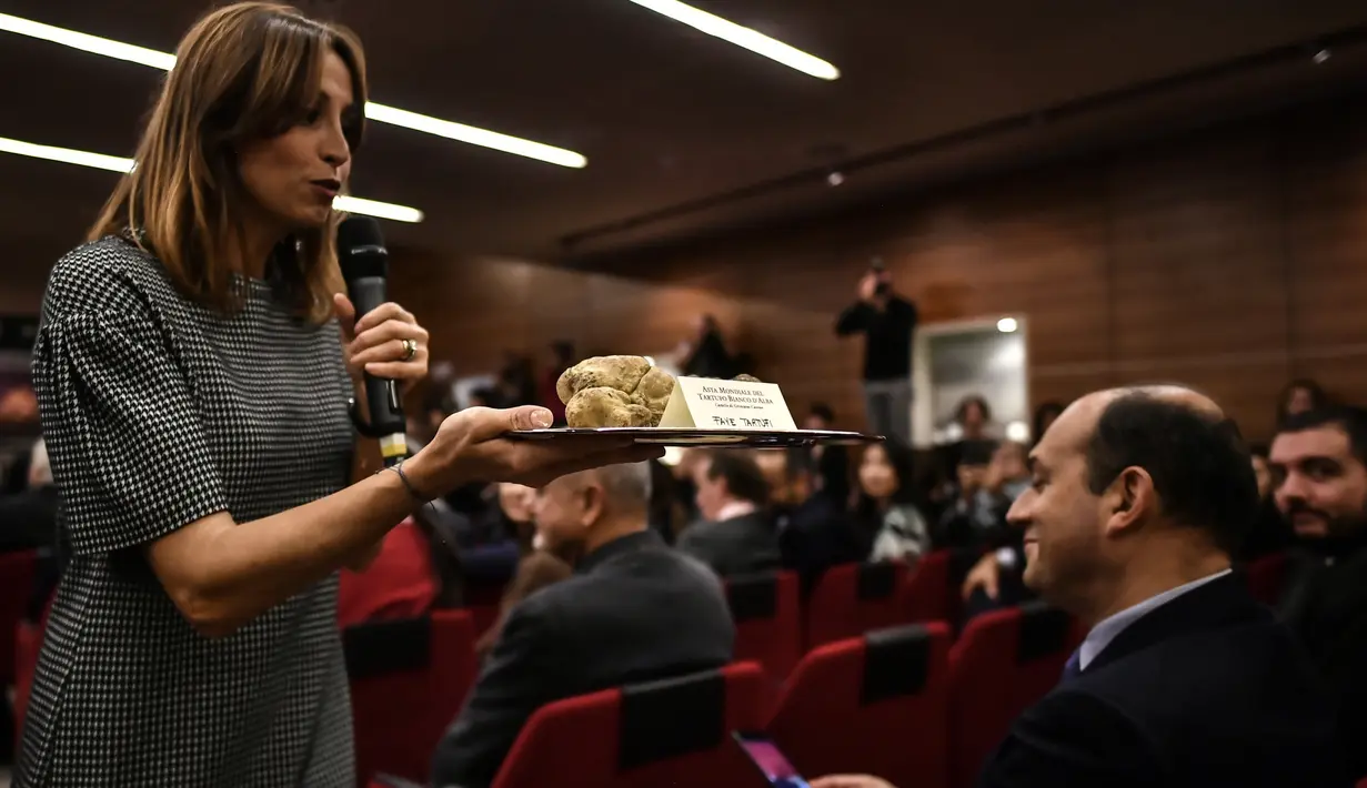 Seorang wanita menampilkan jamur truffle putih langka seberat 850 gram selama lelang World White Truffle ke-19 di Alba, Italia, 11 November 2018. Kota Alba sudah menyelenggarakan lelang jamur truffle putih langka selama 88 tahun. (Marco BERTORELLO/AFP)