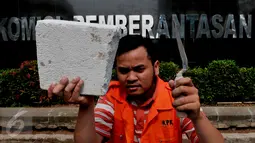 Anggota Koalisi Pemantau Peradilan menunjukkan batu saat aksi peletakkan batu pertama pembangunan museum KPK di halaman KPK, Jakarta, Kamis (8/10/2015). Mereka memprotes DPR yang berencana merevisi UU KPK NO.30 th 2002 (Liputan6.com/Andrian M Tunay)