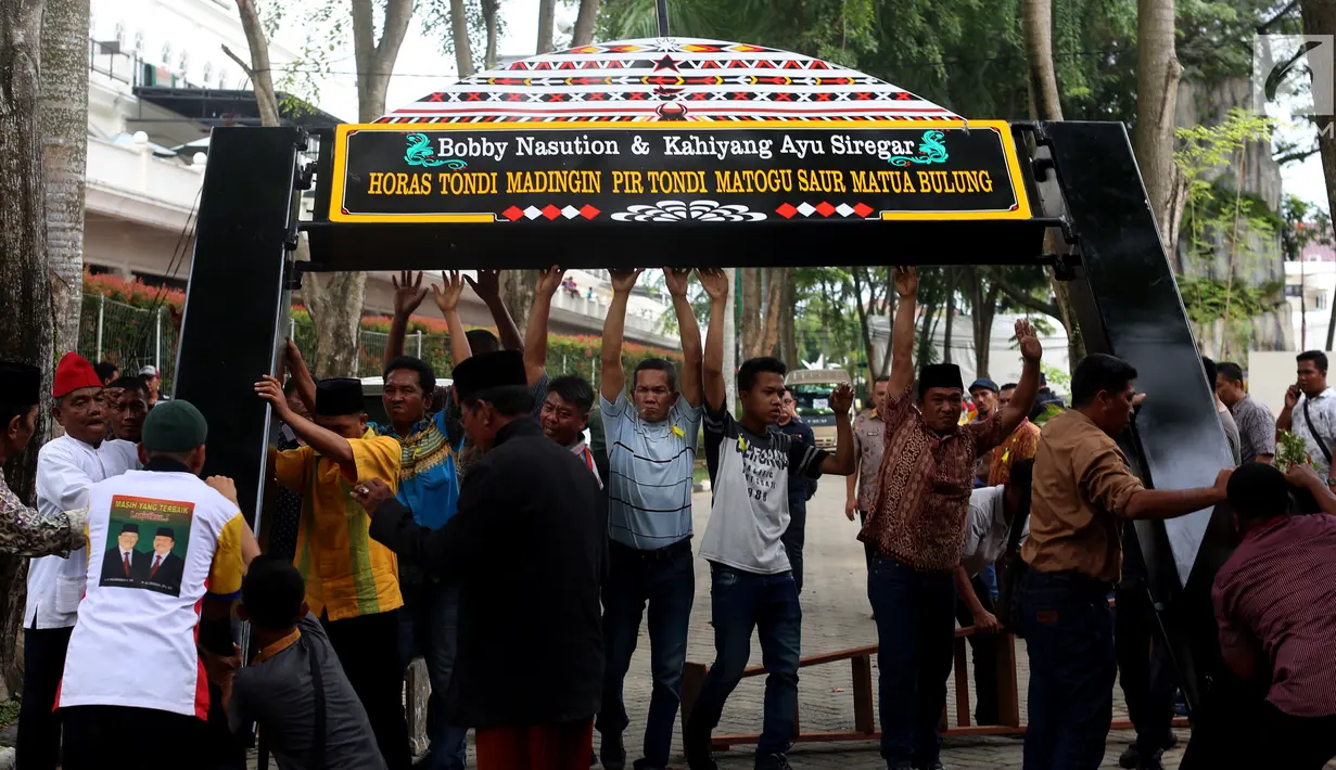 Pekerja memasang gapura menyambut tamu acara ngunduh mantu Kahiyang Ayu dan Bobby Nasution di Komplek Bukit Hijau Regency, Medan, Kamis (23/11). Rangkaian upacara adat dan resepsi Kahiyang dan Bobby dilangsungkan 24-26 November. (Liputan6.com/Johan Tallo)