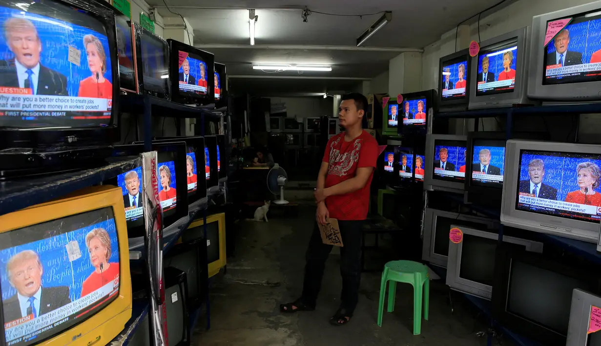 Seorang pekerja menyaksikan debat pertama kedua capres AS dari Partai Republik dan Partai Demokrat, Donald Trump dan Hillary Clinton dari layar televisi di sebuah toko elektronik di metro Manila, Filipina, Selasa (27/9). (REUTERS/Romeo Ranoco)