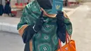 Berada di Arab Saudi, Umi Pipik mencoblos dengan gamis dan cadar hitam dipadukan pashmina hijau sambil membawa tas Prada orange. [@_ummi_pipik_]