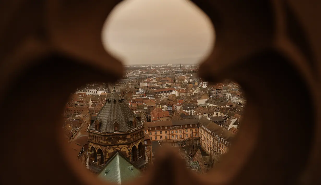 Pemandangan kota Strasbourg tampak diselimuti debu Sahara berwarna oranye bergerak di atas kota di Prancis timur (15/3/2022). Badai di gurun Sahara menciptakan badai besar hembusan angin, yang mengangkat pasir ke udara. (AP Photo/Jean-Francois Badias)