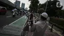 Petugas mengajak pengendara untuk mengambil takjil di Kompleks Masjid Al-Azhar, Jakarta, Kamis (15/4/2021). Pengelola masjid menyiapkan 500 bungkus takjil setiap harinya untuk pengendara yang dibagikan dengan sistem drive thru untuk mencegah penyebaran COVID-19. (Liputan6.com/Johan Tallo)