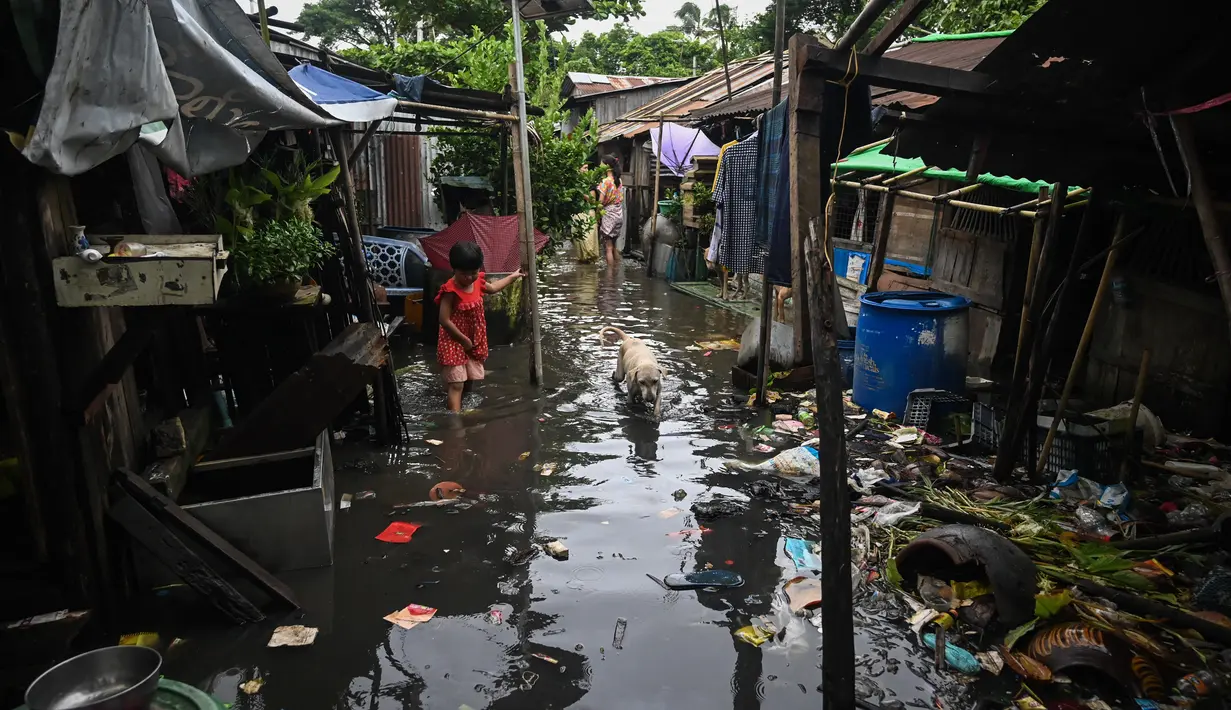 Seorang gadis mengarungi banjir di pinggiran Yangon (17/8/2022). Hujan lebat sejak larut malam 16 Agustus menyebabkan kemacetan lalu lintas dan kesulitan bagi para komuter di kota Yangon dengan beberapa jalan masih terendam banjir.  (AFP/Stringer)