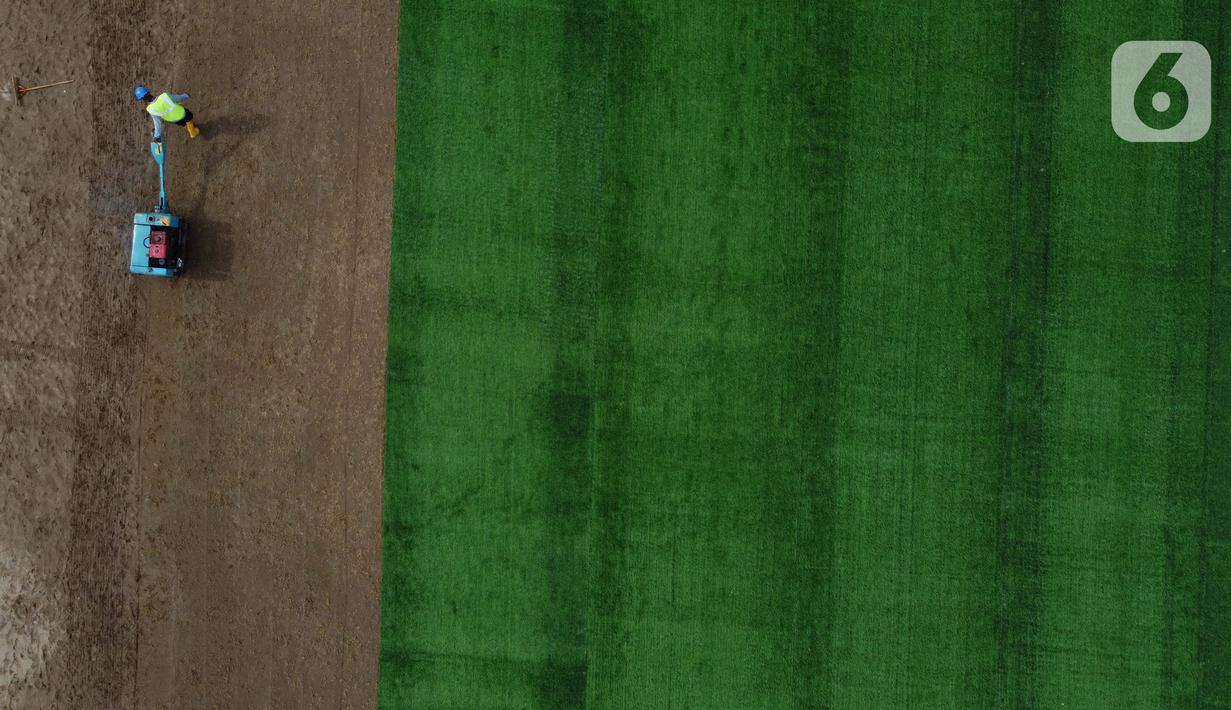 Pekerja melakukan proses perataan tanah untuk pemasangan rumput hybrid di area lapangan latih Jakarta International Stadium, Jumat (23/10/2020). Sebanyak dua lapangan latih JIS mulai dilakukan pemasangan rumput hybrid dan ditarget selesai pada Desember 2020. (Liputan6.com/Helmi Fithriansyah)