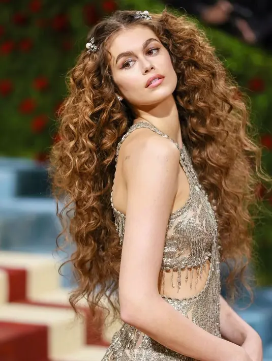 <p>Dalam penampilan keduanya di Met Gala, rambutnya dibuat ikal dengan volume ekstra. Alisnya tebal dan tersisir rapi serta eyeshadow glitter keunguan yang membuatnya terlihat seperti seorang peri. (Foto: Instagram @kaiagerber)</p>