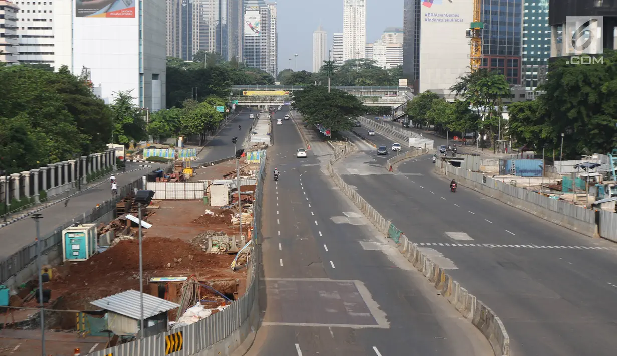 Sejumlah kendaraan melintas di Jalan Thamrin, Jakarta, Jumat (15/6). Pada Hari Raya Lebaran hari pertama, sejumlah ruas jalan di Jakarta tampak sepi dan lengang, berbeda dengan kondisi normal yang padat dan macet. (Liputan6.com/Arya Manggala)