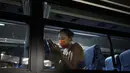 Wang Fan asal Tiongkok, berinteraksi dengan telepon selular saat berada di dalam bus usai pertandingan voli pantai putri Olimpiade Tokyo 2020 melawan Brasil, Selasa (27/7/2021). (Foto: AP/Felipe Dana)