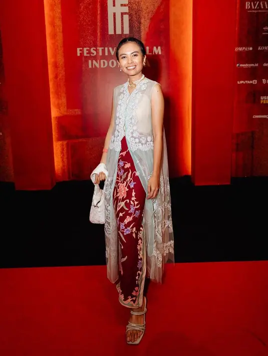 Kamila juga memadukannya dengan heels strap warna silver, sambil membawa handbag putihnya. Ia juga tampil dengan aksesori kalung dan anting-antingnya.  [@kamilaandini]