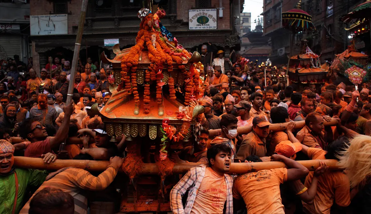 Warga menggotong kereta dewa saat perayaan sindoor Jatra festival di Bhaktapur, Nepal (15/4). Perayaan ini untuk menyambut datangnya musim semi dan Tahun Baru. (AP Photo/Niranjan Shrestha)