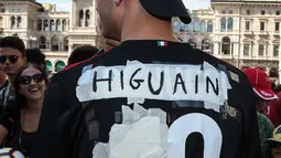Seorang tifosi AC Milan mengenakan jersey bernama Higuain sebelum kedatangan pemain Argentina tersebut di alun-alun pusat Milan Piazza Duomo (3/8). Higuain akan membela I Rossoneri hingga 30 Juni 2019 dengan status pinjaman. (AFP Photo/Stringer)