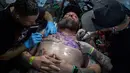 Dua seniman tato sedang berkarya di tubuh seorang pria saat acara Tattoo Week tahunan di Rio de Janeiro, Brasil (12/1). Ajang perhelatan seniman dan penggemar tato ini diadakan setiap tahunnya di Brasil. (AFP Photo/Mauro Pimentel)
