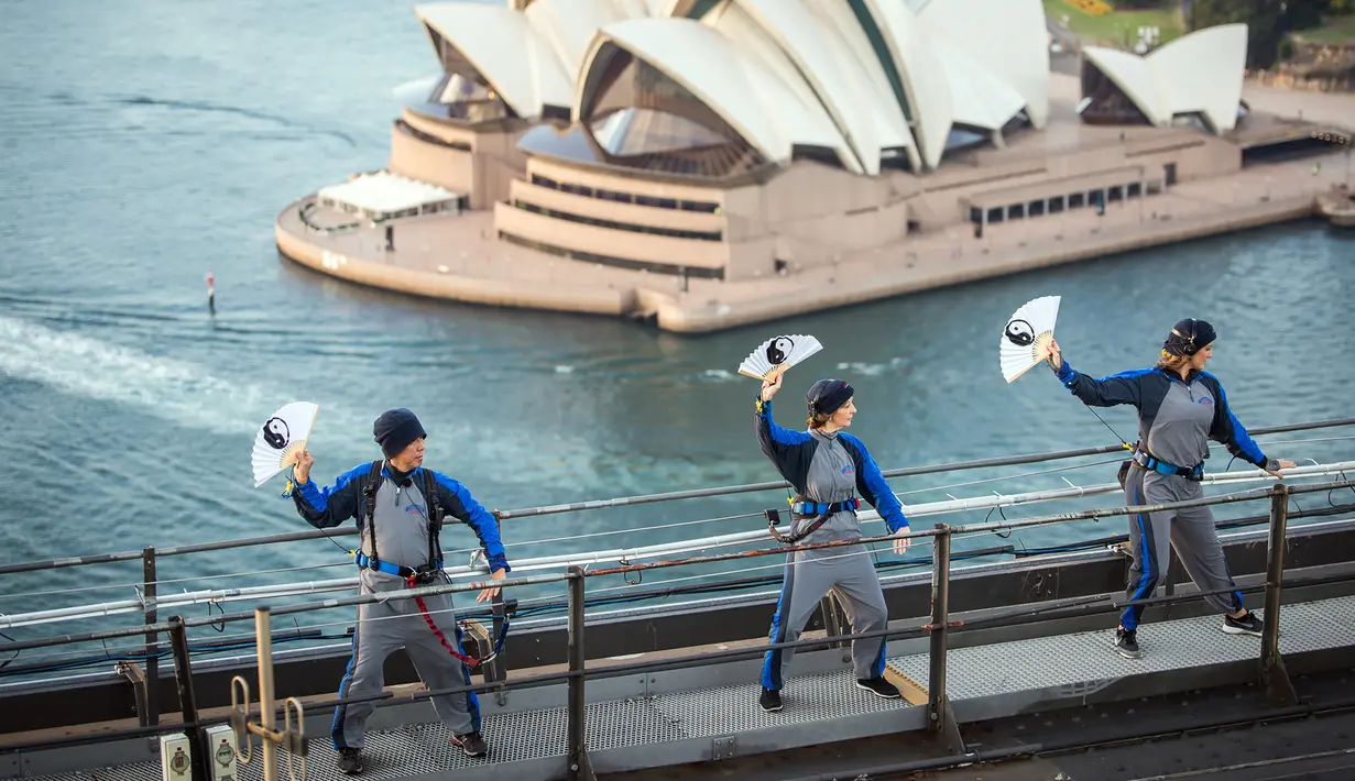 Anggota akademi Tai Chi dan Qigong Australia melakukan latihan Tai Chi di atas Jembatan Sydney Harbour, Australia, Selasa (2/5). Demi keselamatan, mereka dilengkapi tali pengaman yang dikaitkan di pagar besi. (Handout / BRIDGECLIMB SYDNEY / AFP)