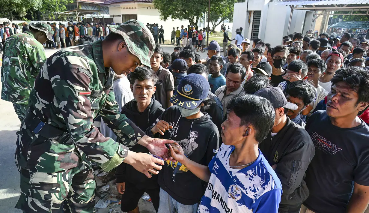 Pihak pemerintah bahwa menyebut cadangan pangan di wilayah itu mencukupi, namun terkendala masalah distribusi akibat akses jalan terputus. Tampak dalam foto, warga desa antre untuk menerima bahan pangan pokok gratis yang didistribusikan di tengah upaya bantuan dari gudang beras pemerintah di Sarudik, Tapanuli Tengah, Provinsi Sumatra Utara, pada Rabu 3 Desember 2025. (YT Hariono/AFP)