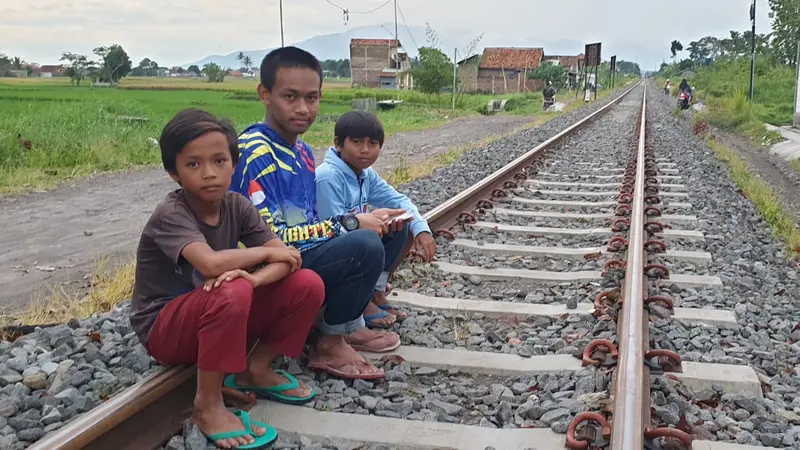 Tiga anak-anak terlihat duduk di atas bantaran rel kereta api Stasiun Garut, Jawa Barat ngabuburit sambil menunggu waktu iftor tiba.