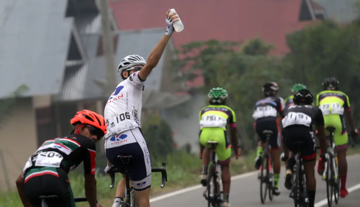 Seorang pebalap memberi kode kepada mobil pendukung tim untuk mensuplai air minum dalam Etape 7 Tour de Singkarak 2015 antara Pasaman-Pasaman Barat, Jumat (9/10/2015). (Bola.com/Arief Bagus)