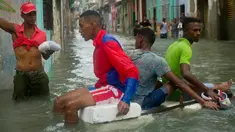 Sejumlah pria menggunakan styrofoam untuk melewati jalanan yang terendam banjir di Hanava, Kuba, Minggu (10/9). Badai irma yang melanda pantai timur Perairan Kuba pada Jumat waktu setempat menyebabkan sebagian kota terendam banjir. (AP/Ramon Espinosa)