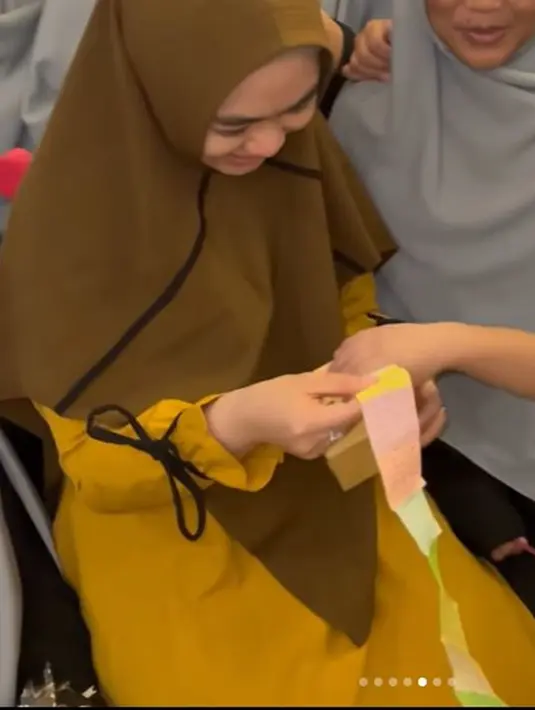 Para santri juga menyiapkan hadiah khusus untuk sang ustazah yang dipanggil Umma itu. Selain memberikan buket dan bingkai, para santri juga mempersembahkan sebuah kotak berisi deretan ucapan dan doa baik untuknya yang dirangkai memanjang. Ibu empat anak itu pun langsung membacanya satu per satu. (Liputan6.com/IG/@okisetianadewi)