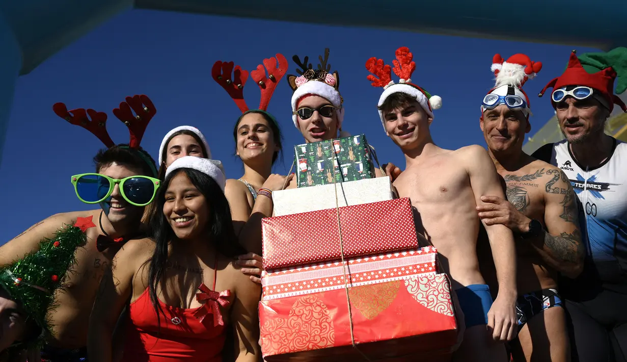 Para peserta mengenakan kostum bernuansa natal seperti topi Santa Klaus dan topi tanduk rusa saat mengikuti tradisi lomba renang unik saat natal di pelabuhan tua Barcelona (Port Vell Barcelona), Spanyol, Senin (25/12/2023) waktu setempat. Lomba tersebut dimenangkan oleh Edward Poeschke dengan mencatatkan waktu 3 menit 17 detik. (AFP/Josep Lago)