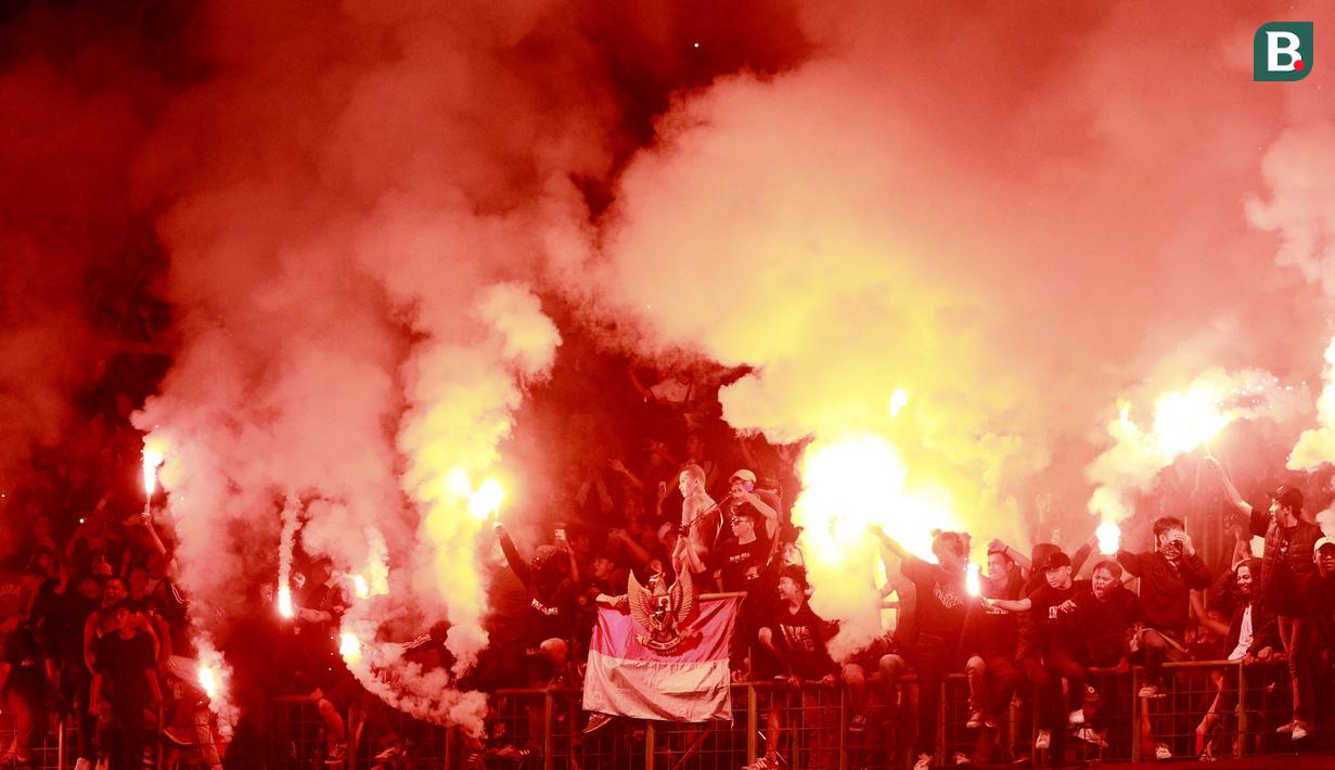 Suporter menyalakan flare usai laga Timnas Indonesia U-19 melawan Myanmar pada laga Piala AFF U-19 2022 di Stadion Patriot Candrabhaga, Bekasi, Minggu (10/7/2022). (Bola.com/M Iqbal Ichsan)